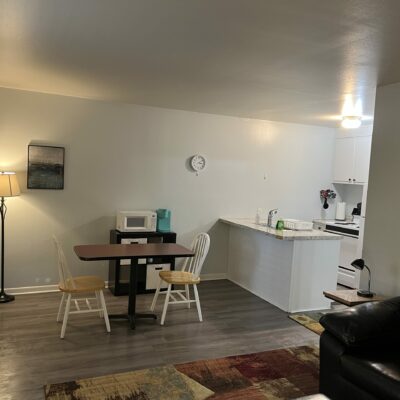 apartment living space featuring a very small table and two chairs, a tall lamp, and the opening of the kitchen